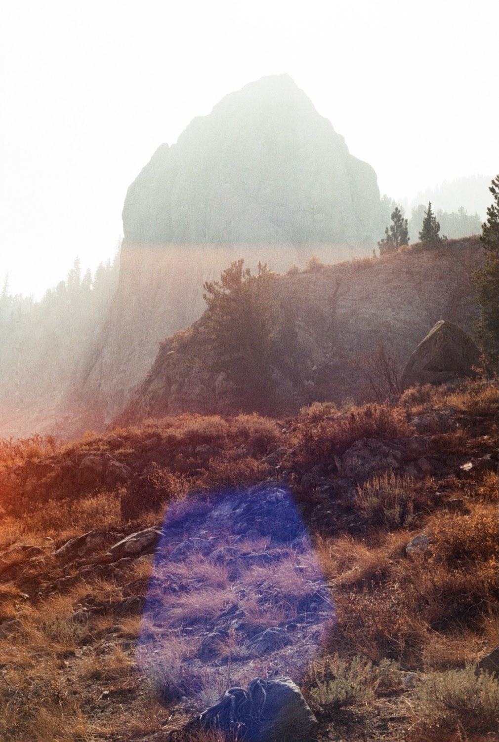 Morning sun over a rocky peak and autumn brush