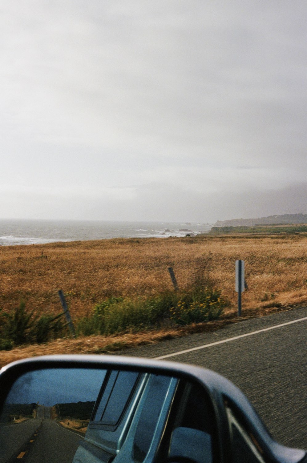 A coast road and ocean seen from a car window