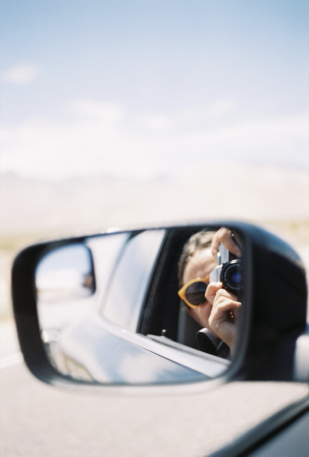 A self-portrait in a car's side mirror